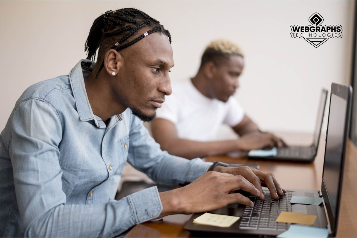 Two students working on laptops during a design class